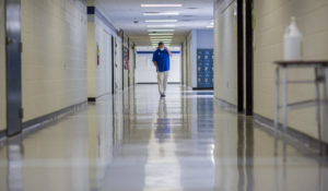A middle school principal walks the empty halls of his school as he speaks with one of his teachers to get an update on her COVID-19 symptoms, Friday, Aug. 20, 2021, in Wrightsville, Ga. On Monday, Dec. 27, 2021, U.S. health officials cut isolation restrictions for Americans who catch the coronavirus from 10 to five days, and also shortened the time that close contacts need to quarantine. (AP Photo/Stephen B. Morton, File)