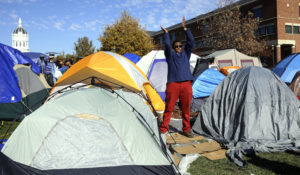 In this Nov. 9, 2015, file photograph, a student claps while standing in a protest movement's camp area following the announcement that University of Missouri System President Tim Wolfe was stepping down at the university in Columbia, Missouri. Wolfe resigned with the football team and others on campus in open revolt over his handling of racial tensions at the school. (AP Photo/Jeff Roberson, File)