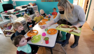Amy McCoy serves lunch to preschoolers at her Forever Young Daycare facility, Monday, Oct. 25, 2021, in Mountlake Terrace, Wash. (AP Photo/Elaine Thompson)