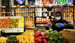A grocer waring a proactive mask as a precaution against the spread of the coronavirus stocks papers at the Reading Terminal Market in Philadelphia, Wednesday, Feb. 16, 2022. Philadelphia city officials lifted the city's vaccine mandate for indoor dining and other establishments that serve food and drinks, but an indoor mask mandate remains in place. Philadelphia Public Health officials announced that the vaccine mandate was lifted immediately Wednesday.  (AP Photo/Matt Rourke)