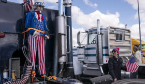 A supporter walks past a mannequin of Uncle Sam at the beginning of a trucker caravan to Washington D.C. called The People’s Convoy on Wednesday, Feb. 23, 2022, in Adelanto, Calif. (AP Photo/Nathan Howard)