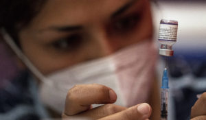 Health workers prepare doses of the Pfizer vaccine for COVID-19 at a start a second booster shot campaign against the new coronavirus, at a sports facility in Santiago, Chile, Monday, Feb. 7, 2022. (AP Photo/Esteban Felix)