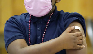 A Jackson Public School student receives a bandage on the arm after receiving a children's dose of the Pfizer COVID-19 vaccine from a nurse, at a vaccination station in Jackson, Miss., Feb. 16, 2022. (AP Photo/Rogelio V. Solis)