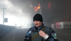 A Ukrainian serviceman walks as fire and smoke rise over a building following shelling in Kyiv, Ukraine, on Thursday. (AP Photo/Efrem Lukatsky)