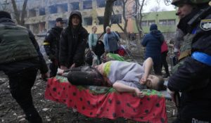 Ukrainian emergency employees and volunteers carry an injured pregnant woman from the damaged by shelling maternity hospital in Mariupol, Ukraine on Wednesday. (AP Photo/Evgeniy Maloletka)