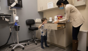 Hudson Diener, 3, peeks into a cabinet during an appointment for a Moderna COVID-19 vaccine trial in Commack, N.Y. on Nov. 30, 2021. On Wednesday, March 23, 2022, Moderna said its COVID-19 vaccine works in babies, toddlers and preschoolers, and if regulators agree it could mean a chance to finally start vaccinating the littlest kids by summer. (AP Photo/Emma H. Tobin)