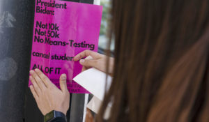 American University student Magnolia Mead puts up posters near the White House promoting student loan debt forgiveness, Friday, April 29, 2022, in Washington. (AP Photo/Evan Vucci)