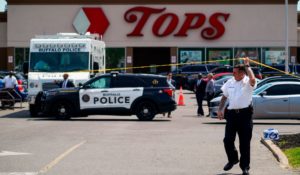 A police officer lifts the tape on Sunday to cordon off the scene of a shooting at a supermarket in Buffalo, N.Y. (AP Photo/Matt Rourke)