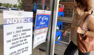 A customer checks information signs as she walks to a grocery store Saturday, July 2, 2022, in Mount Prospect, Ill. The state sales tax on groceries in Illinois will be suspended for a year starting Friday, July 1, 2022., under the state budget approved in April. (AP Photo/Nam Y. Huh)