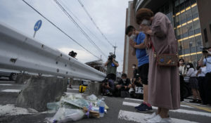 People pray after putting a bouquet of flowers at a makeshift memorial at the scene where the former Prime Minister Shinzo Abe was shot, Friday, July 8, 2022. (AP Photo/Hiro Komae)