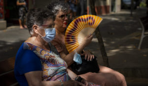 A woman fans herself sitting on a bench on a street in Barcelona, Spain, Wednesday, July 20, 2022, as the country faced a sweltering heat wave. (AP Photo/Emilio Morenatti)