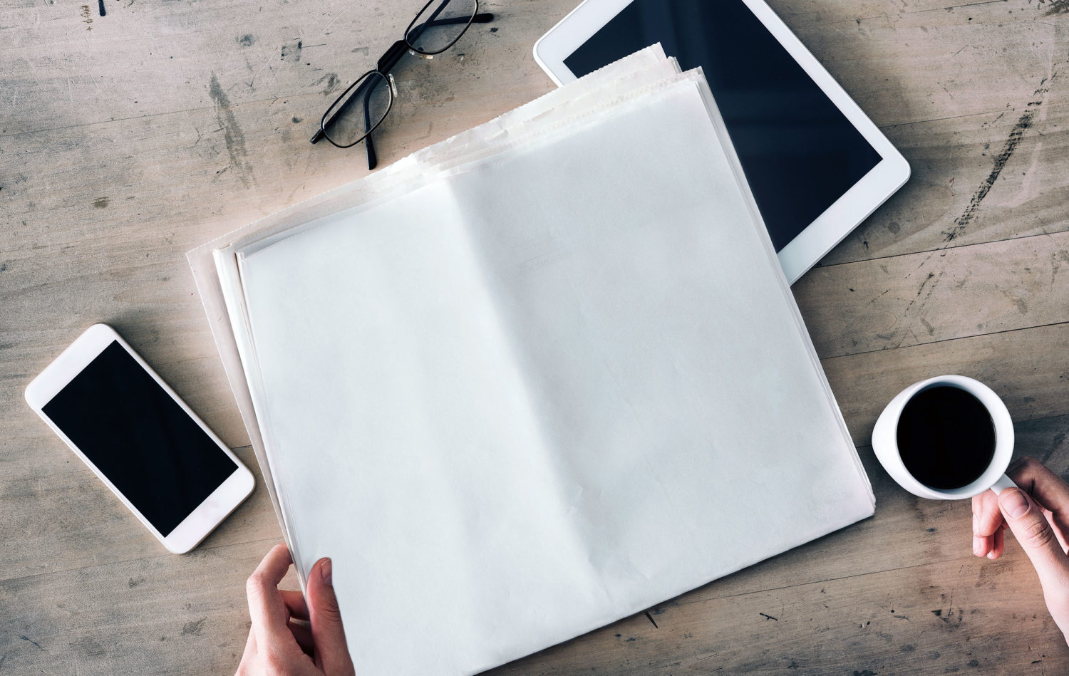 Woman holding empty newspaper on wooden table