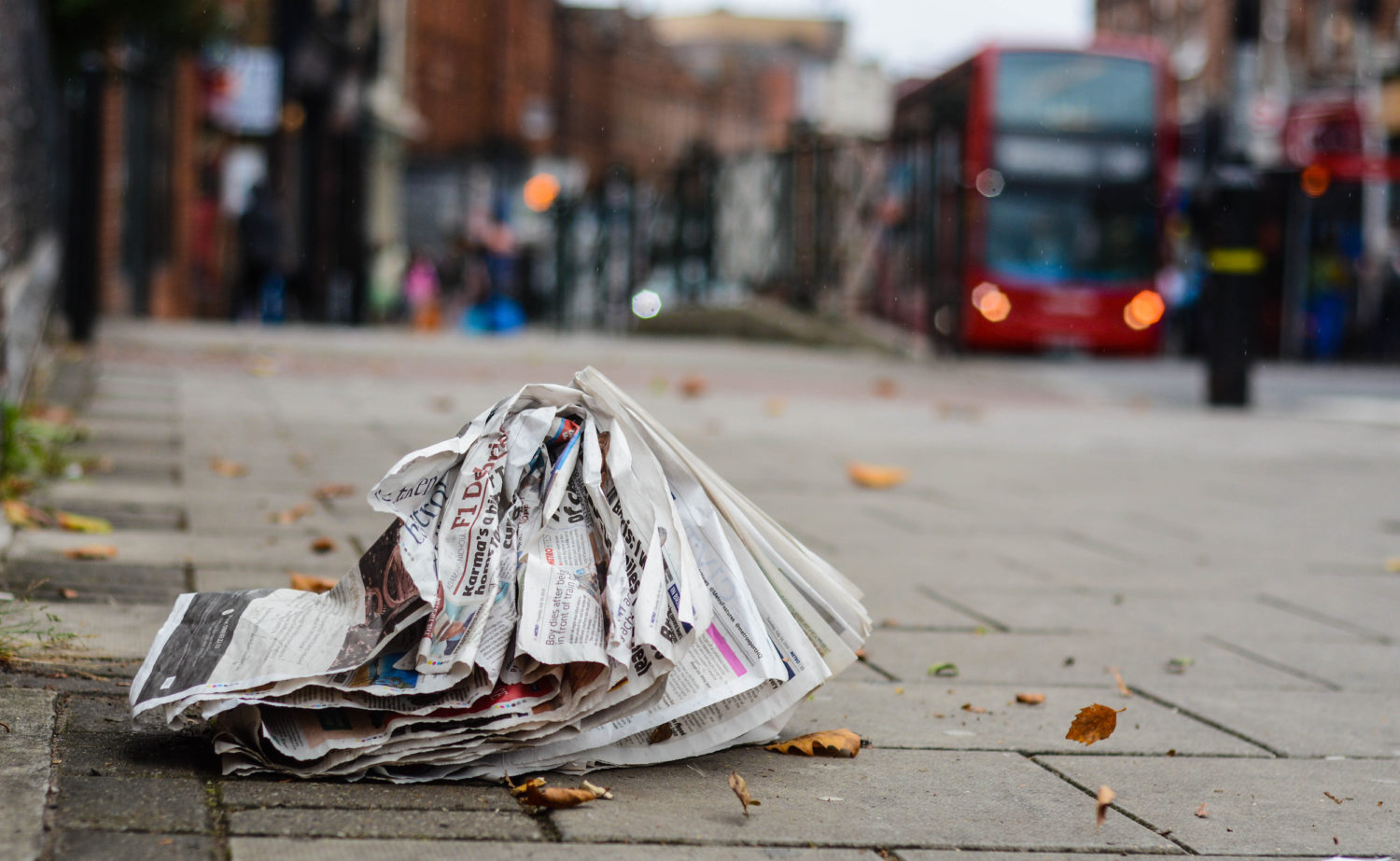 A newspaper flutters carelessly on the ground.