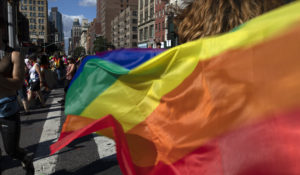 In this June 30, 2019, file photo parade-goers carrying rainbow flags walk down a street during the LBGTQ Pride march in New York, to celebrate five decades of LGBTQ pride, marking the 50th anniversary of the police raid that sparked the modern-day gay rights movement. (AP Photo/Wong Maye-E, File)