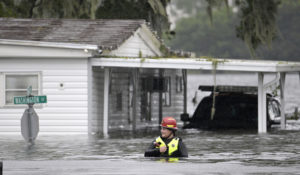 A first responder with Orange County Fire Rescue makes her way through floodwaters looking for residents of a neighborhood needing help in the aftermath of Hurricane Ian, Thursday in Orlando, Florida. (AP Photo/Phelan M. Ebenhack)