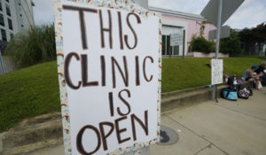 A sign outside the Jackson Women's Health Organization clinic in Jackson, Mississippi, assures potential patients on July 3, 2022, that it is open. The clinic has since closed it doors. (AP Photo/Rogelio V. Solis)