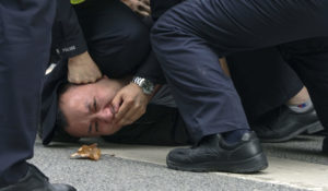 Policemen pin down and arrest a protester Sunday during a demonstration over COVID-19 restrictions on a street in Shanghai, China. (AP photo)