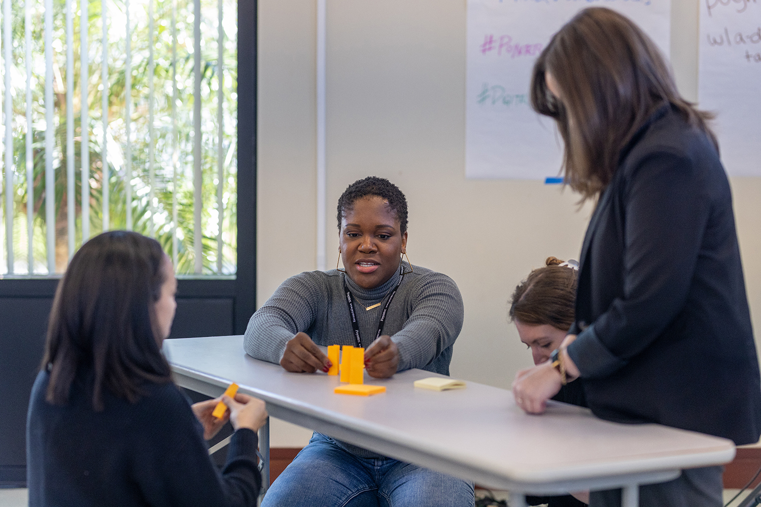 Three people around a table stacking orange sticky notes.