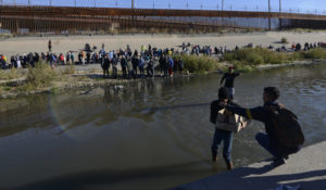 Migrants cross the Mexico-U.S. border from Ciudad Juarez, Mexico, to surrender to U.S. Border Patrol agents on Monday. According to the Ciudad Juarez Human Rights Office, hundreds of mostly Central American migrants arrived in buses and crossed the border to seek asylum in the U.S. after spending the night in shelters. (AP Photo/Christian Chavez)