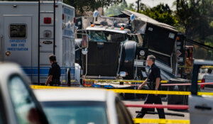 Police officers walk past the remains of an armored Los Angeles Police Department tractor-trailer in 2021 after seized fireworks exploded, causing property damage and injuries in south Los Angeles. (AP Photo/Damian Dovarganes, File)