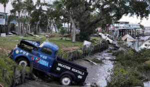 Pickup trucks and debris lie strewn in a canal in Horseshoe Beach, Fla., after the passage of Hurricane Idalia, Wednesday, Aug. 30, 2023. (AP Photo/Rebecca Blackwell)