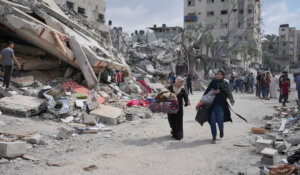 Palestinian women walk by buildings destroyed in Israeli airstrikes in Nuseirat camp in the central Gaza Strip, Monday, Oct. 16, 2023. (AP Photo/Hatem Moussa, File)