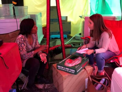 Report for America corps member Rachel Crumpler interviews Tonga Ramseur, owner of Ethio-Indi Alkaline & Vegan Cuisine, at the NC State Fair for North Carolina Health News. (Rose Hoban/North Carolina Health News)