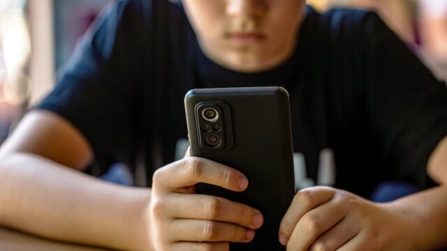 Child boy with cell phone, holds smartphone.