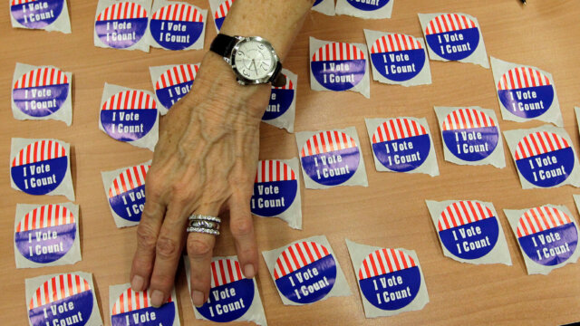 A hand sets out I Voted stickers on a table