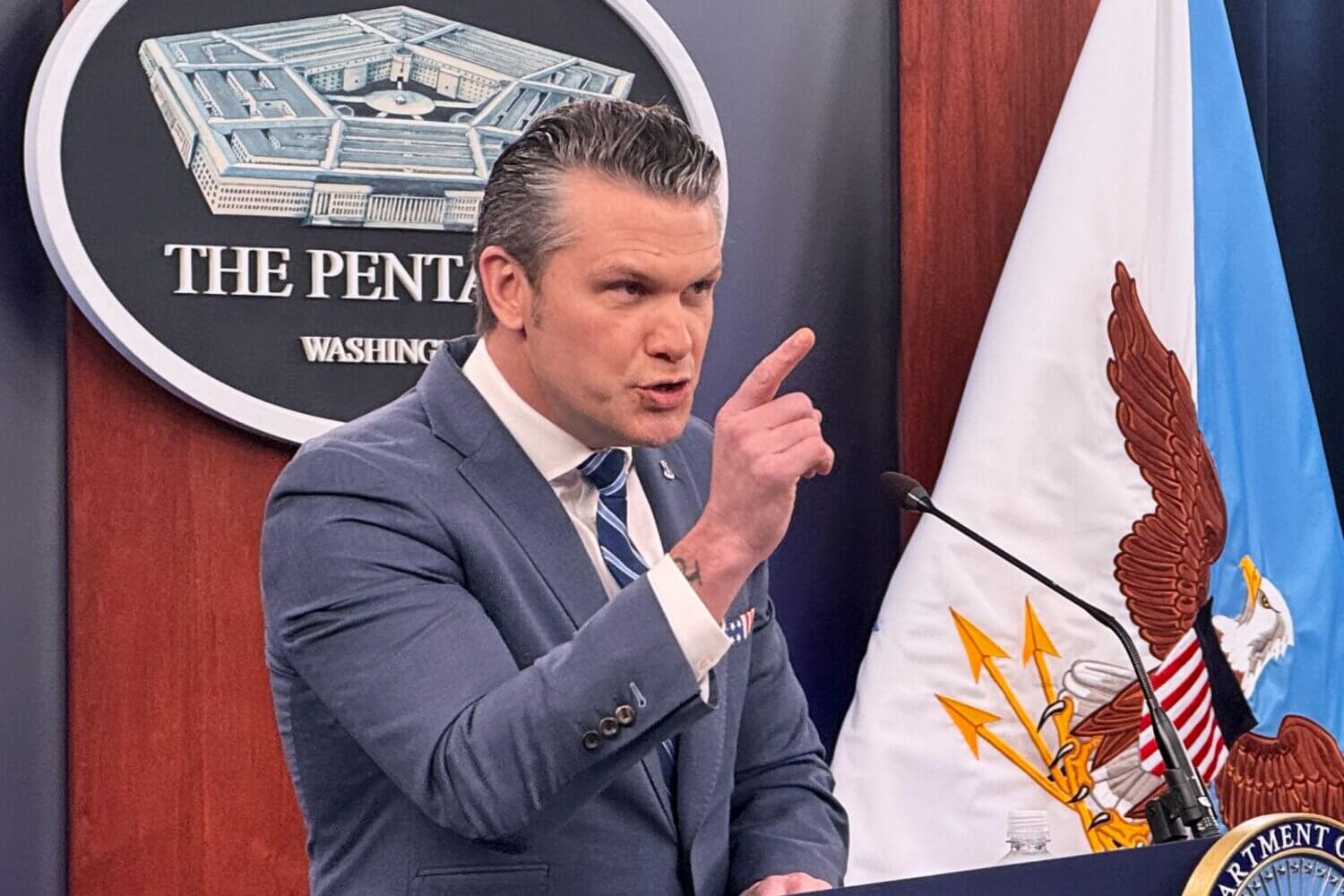 A middle-aged white man in a suit standing at a podium points his finger and is seemingly scolding whoever he is talking to