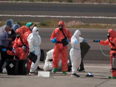 Passengers are sprayed with disinfectant by Spanish government officials before boarding a plane after disembarking from the hantavirus-stricken cruise ship MV Hondius at Tenerife airport in the Canary Islands, Spain, Sunday, May 10, 2026. (AP Photo/Arturo Rodriguez)