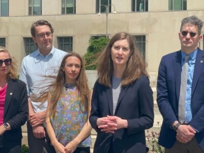 Attorney Carrie DeCell, second from right, speaks about her client's lawsuit against a Trump administration visa policy outside the federal courthouse in Washington, D.C., on May 13, 2026. (Louis Jacobson/Poynter)