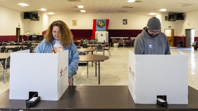 A woman and a man casting their 2026 primary election ballots at a polling location in Indianapolis.